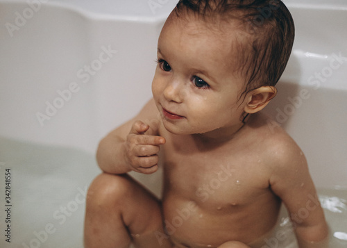 selective focus, noise effect: family is washing and bathing the baby in the bathroom, child girl have fun, she is happy and smiling, likes to enjoy water