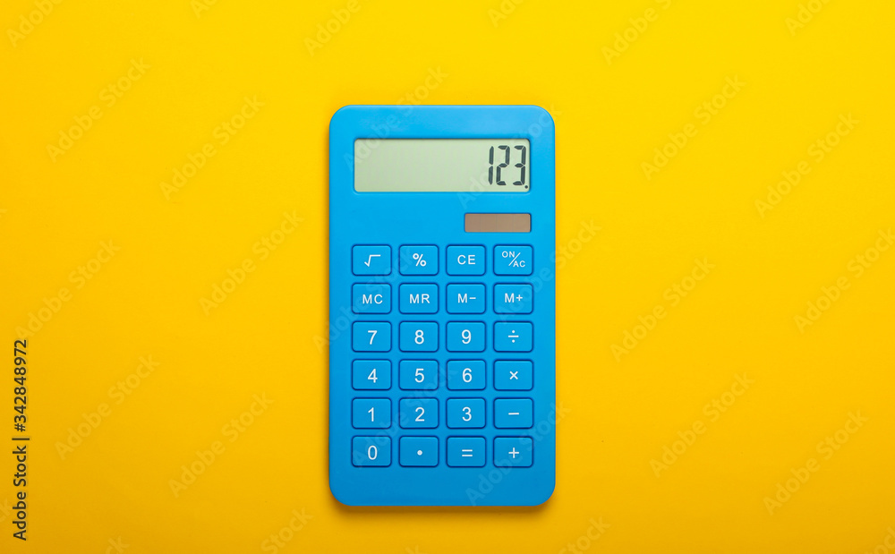 Blue calculator on a yellow background. Calculation or counting. Minimalism. Top view Blue calculator on a yellow background. Calculation or counting. Minimalism. Top view