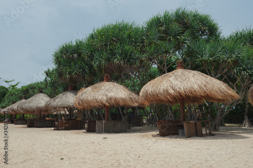 Beach umbrellas from straw on tropical sandy beach.