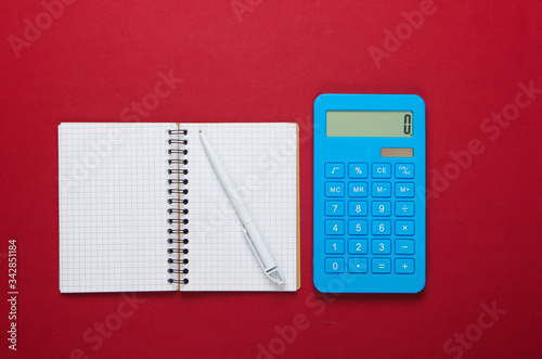 Calculator with notebook on red background. Education process. Top view. Flat lay