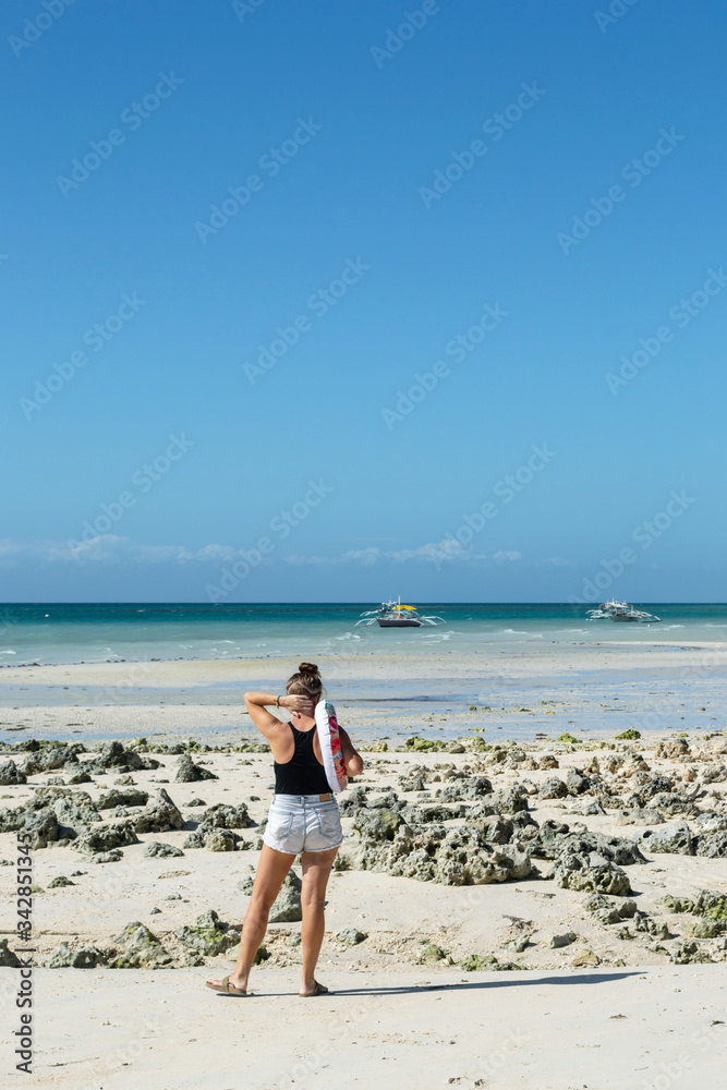 Young woman in shorts standing by the sea with swimming circle in tropical Philippines