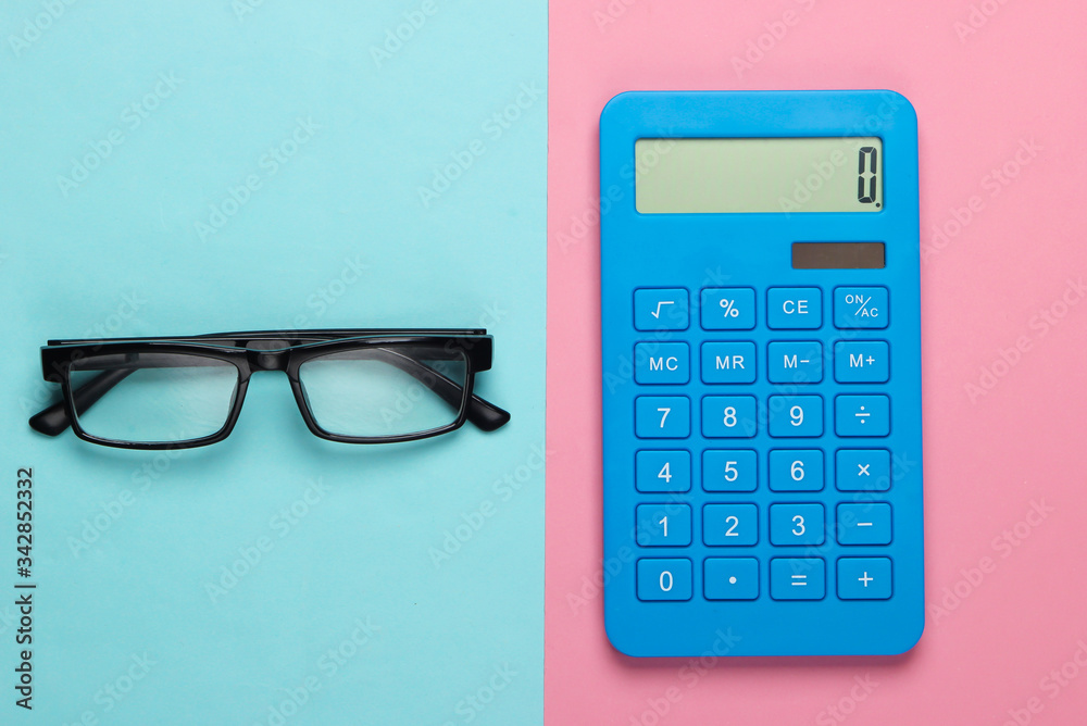 Calculator and glasses on a blue-pink pastel background. Secretary, economist or office worker concept. Top view Calculator and glasses on a blue-pink pastel background. Secretary, economist or office worker concept. Top view