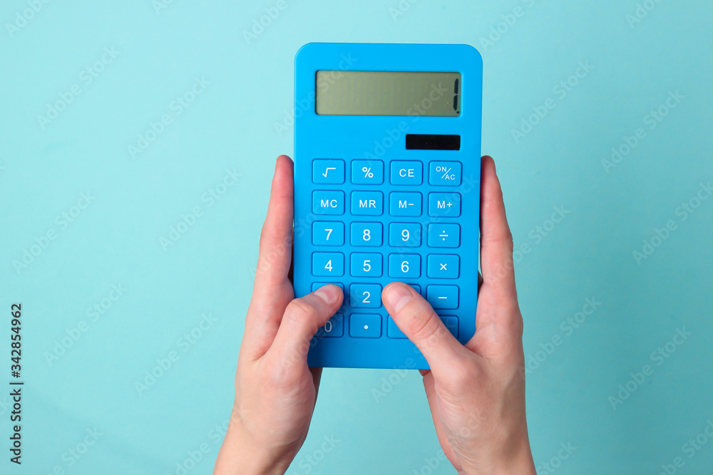 The hand presses the buttons blue calculator on blue background. The hand presses the buttons blue calculator on blue background.