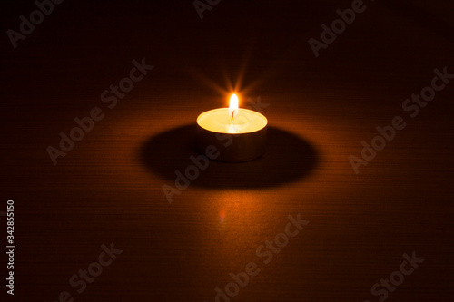 candle burning in the dark on woody background