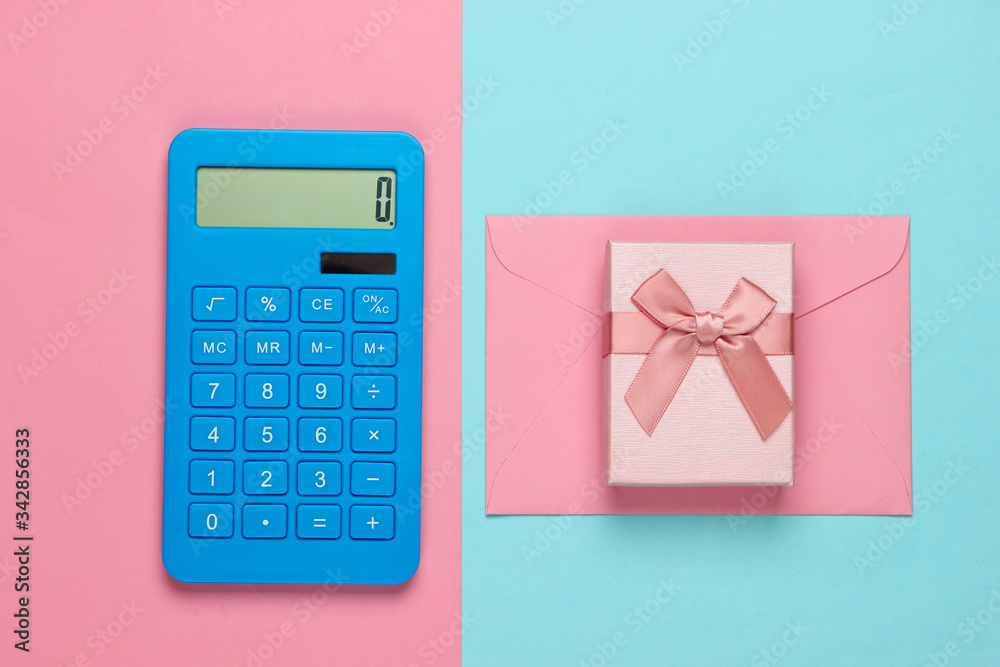 Calculator with envelope and gift box on pink-blue pastel background. Top view Calculator with envelope and gift box on pink-blue pastel background. Top view