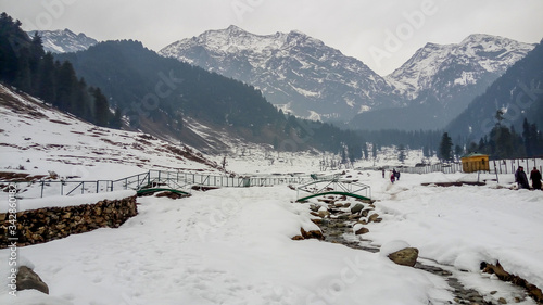 Snow landscape & glacial water stream with all snowy 
Himalaya mountains in Aru Valley, Pahalgam. Snow covered forest during Christmas/New Year holidays in Kashmir, India.
