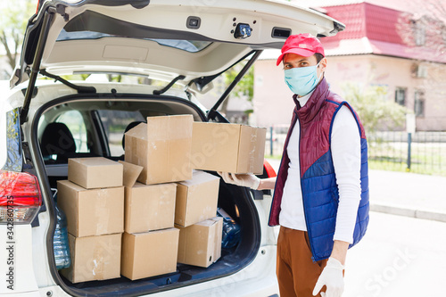 Delivery man holding paper bag with food near the car, food delivery man in protective mask