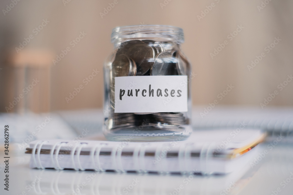 Savings concept for purchases - Glass jar with coins and inscription.