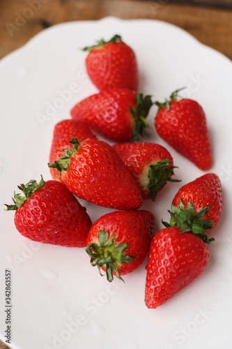 Juicy strawberries in a white plate on the table 
