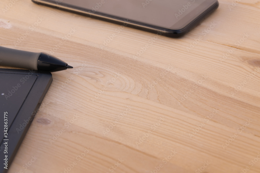 Graphic tablet and mobile black on a wooden background and copy space. Technology concept. Graphic tablet and mobile black on a wooden background and copy space. Technology concept.