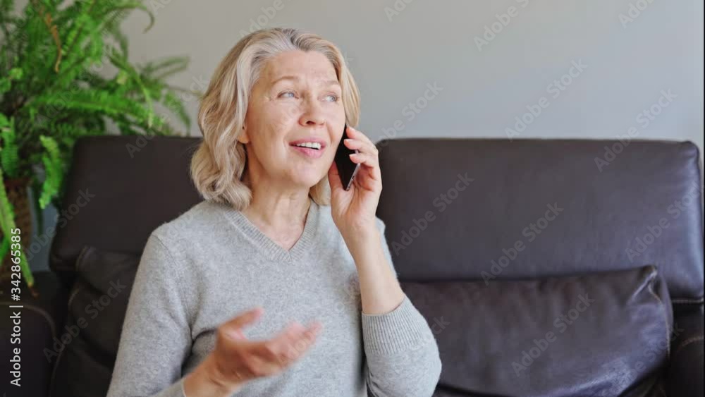 mature woman using mobile phone while sitting on sofa at home mature woman using mobile phone while sitting on sofa at home