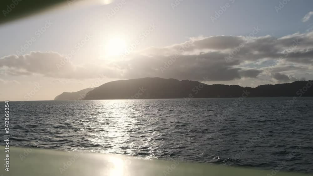A sunset view over choppy seas from a boat with mountains in the background in slow motion A sunset view over choppy seas from a boat with mountains in the background in slow motion