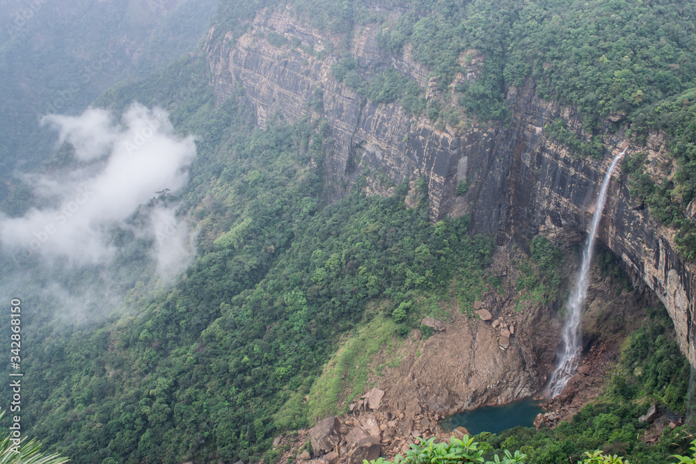 The Nohkalikai waterfall, tallest plunge waterfall in India. Fallen deep into the valley through rocky mountains. Surrounded by thick green forest and clouds during winter trip to Meghalaya, India. 