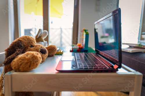 Homeoffice - symbolic photo of a stuffed dog and rabbit which a working on a laptop at home in the living room.