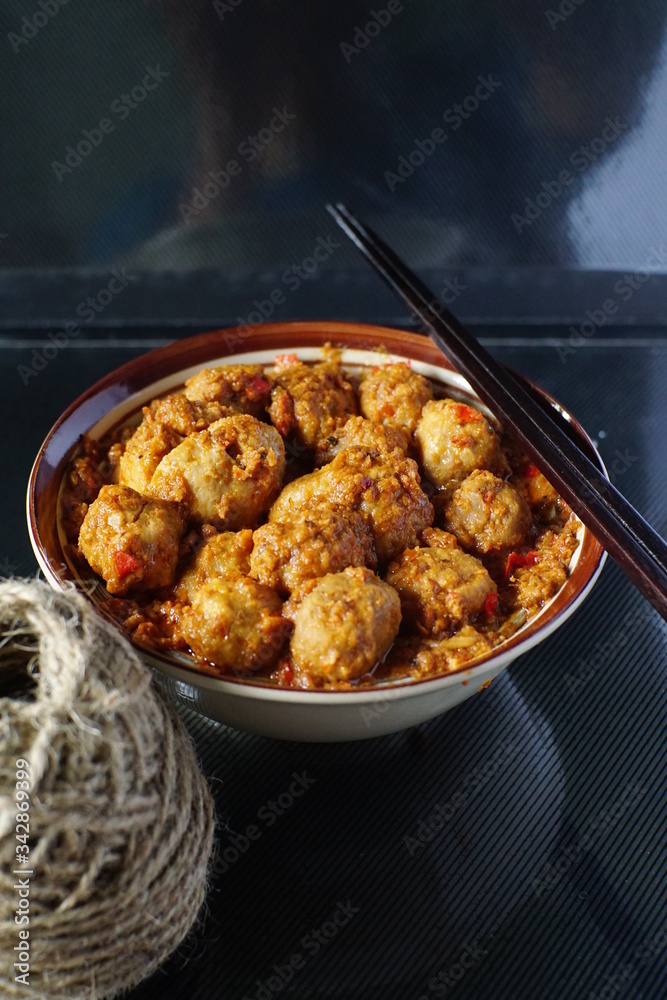 very spicy meatball in a bowl with chopsticks for snacks or lunch in dark background very spicy meatball in a bowl with chopsticks for snacks or lunch in dark background