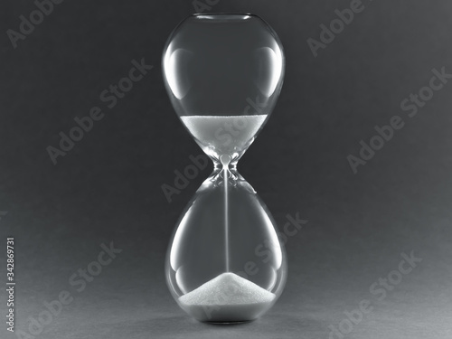 Hourglass on dark background. Symbol of passing time, concept for business deadline, urgency and running out of time..