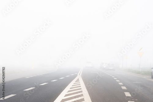 Cars riding on a city street in a foggy autumn morning