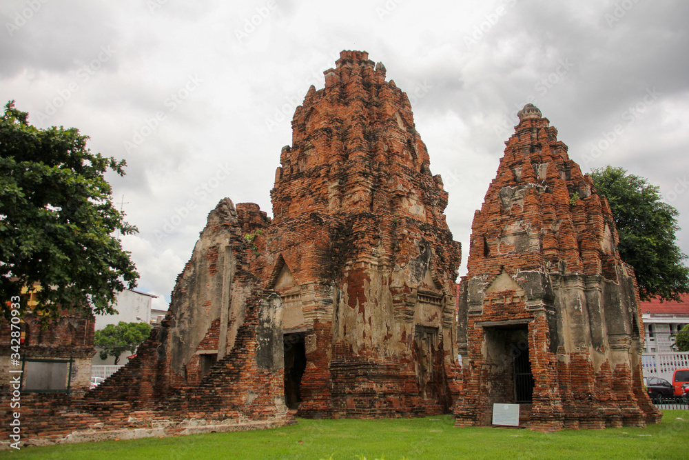 Brown stone temple in Lopburi surrounded by grass