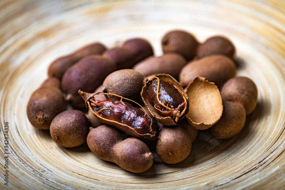 Obraz premium Dried organic exotic tamarind fruits in bamboo bowl closeup. Studio macro shoot