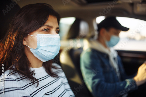 A girl and a boy driving in a car during coronavirus quarantine wearing medical masks. Safe taxi and healthcare during pandemic covid-19. Passangers virus safety concept,