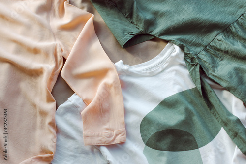 women's clothing in muted shades of green, brown, orange-pink and white is casually laid out