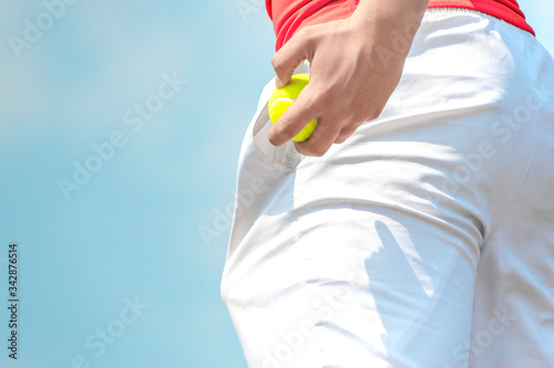 Tennis player prepares for serve, pulling a tennis ball out of his pocket. Start tennis match, tournament, season. Banner. Close up. Copy space for text.
