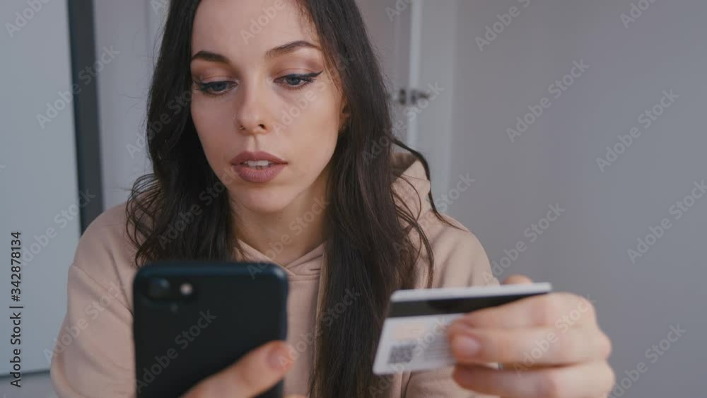 Smiling young woman online banking using smartphone shopping online with credit card at home lifestyle. Easy pay using digital gadget. Smiling young woman online banking using smartphone shopping online with credit card at home lifestyle. Easy pay using digital gadget.