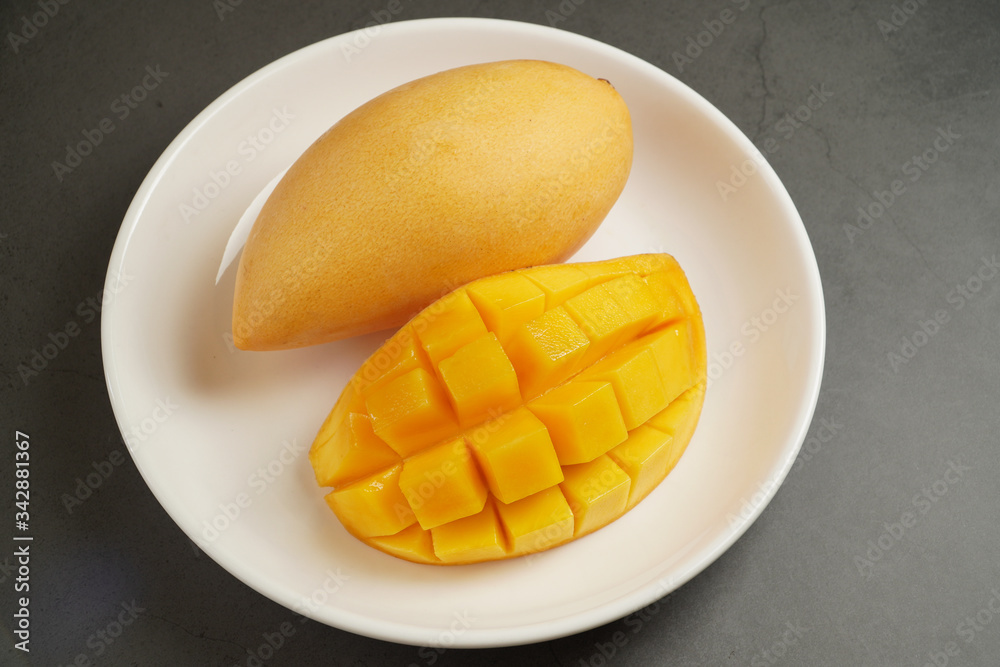 Fresh Mango on white plate and black pattern background Fresh Mango on white plate and black pattern background