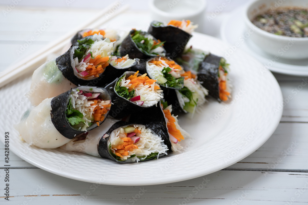 Vietnamese vegan rice paper and nori sheet spring rolls on white plate Vietnamese vegan rice paper and nori sheet spring rolls on white plate