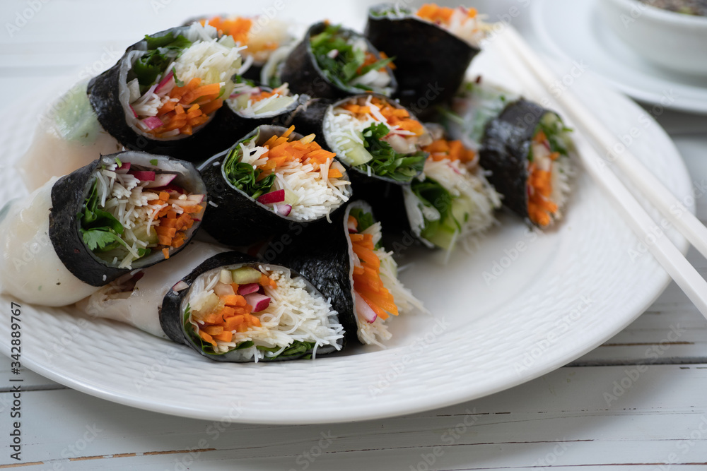 Vietnamese vegan rice paper and nori sheet spring rolls on white plate Vietnamese vegan rice paper and nori sheet spring rolls on white plate