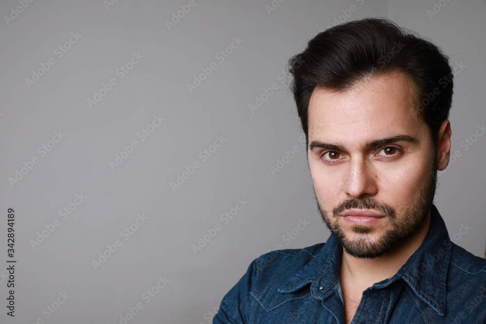 Portrait of 30-year-old man standing over grey background in denim shirt. Close up. Copy-space. Studio shot. Portrait of 30-year-old man standing over grey background in denim shirt. Close up. Copy-space. Studio shot.