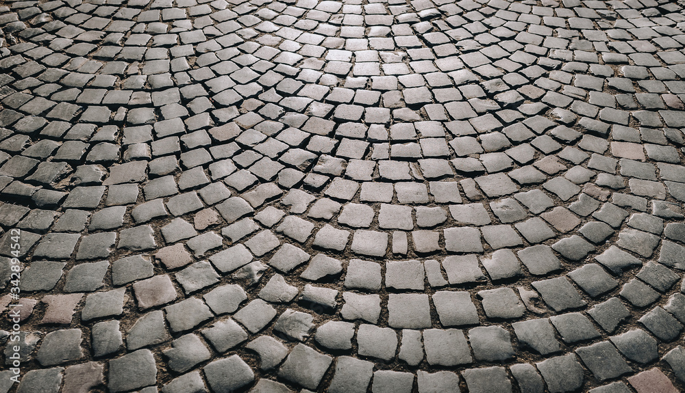 The dark gray paving stones laid out in a semicircle. The texture of the old dark stone. Road surface. Vintage, grunge.