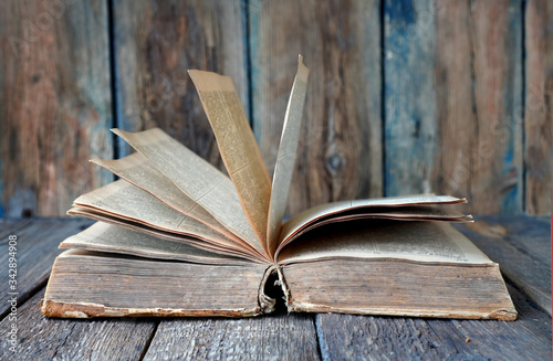 Ancient retro book on a wooden background. Text in the book is not recognizable. photo