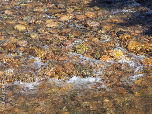 Clear water of mountain stream falling over river stones.