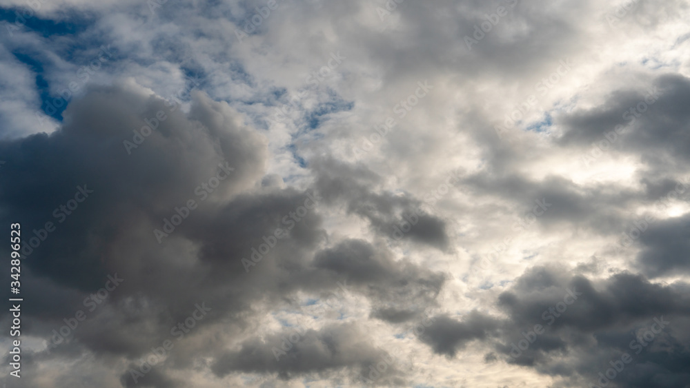 Fototapeta premium A cluster of light and fluffy clouds interspersed with dark gray clouds. Before the rain and the thunderstorm.