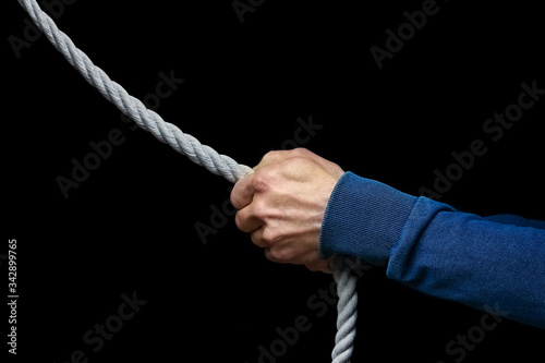 a Hands with a rope on a black background. A man pulls a rope wrestling. Drag the business to your side.