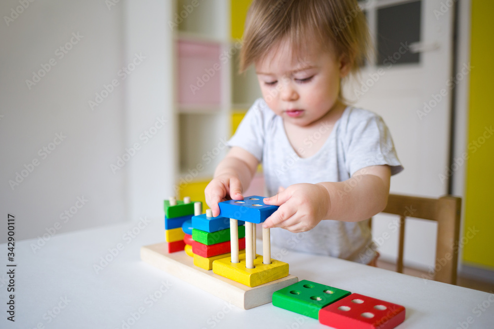 baby plays in the constructor. small child puts the rings on the pins. concept of development of fine motor skills baby plays in the constructor. small child puts the rings on the pins. concept of development of fine motor skills