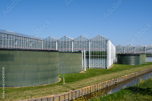 Perspective view of a modern high tech industrial greenhouse with water tanks in front in the Netherlands