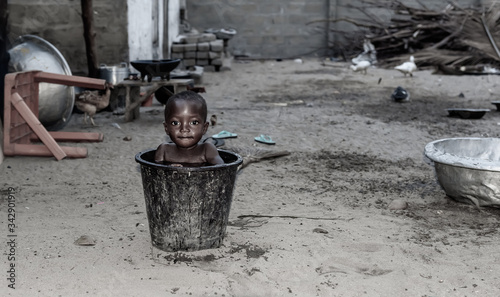 African child cools down in a bucket of water during a hot afternoon. Photo from a fishing village Ada Foah Ghana West Africa.
