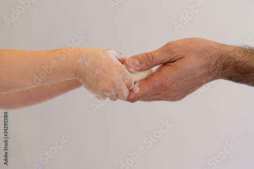 Cropped image of little girl and her father washing hands using soap in bathroom at home