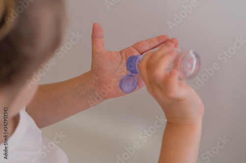 Baby girl uses sanitizer on hand on a white background