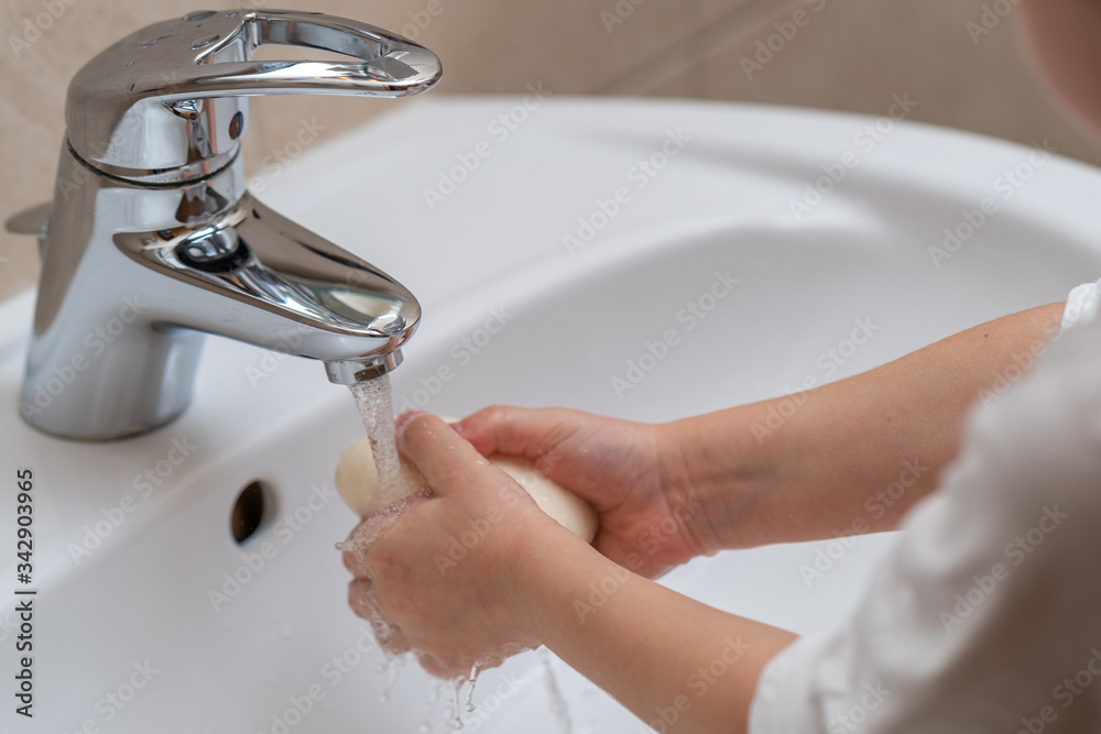 Little girl is washing her hands under water in the white bathroom Little girl is washing her hands under water in the white bathroom