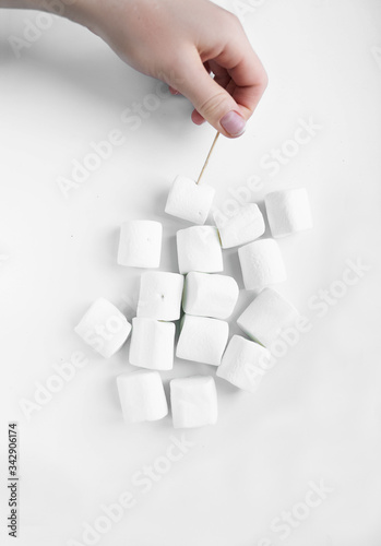 White marshmallows and a hand with a toothpick
