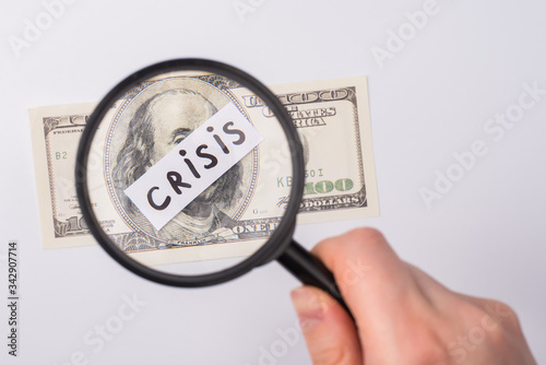 World recession 2020 concept. Cropped close up photo of female hand using magnifier looking at 100 american banknote isolated over grey background