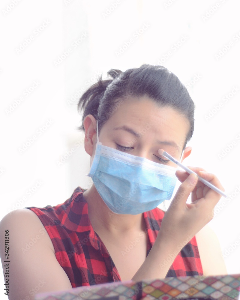 Mujer empresaria con tapabocas o mascara facial poniéndose maquillaje frente al espejo. Preparándose en la mañana para el trabajo en la cuarentena Mujer empresaria con tapabocas o mascara facial poniéndose maquillaje frente al espejo. Preparándose en la mañana para el trabajo en la cuarentena