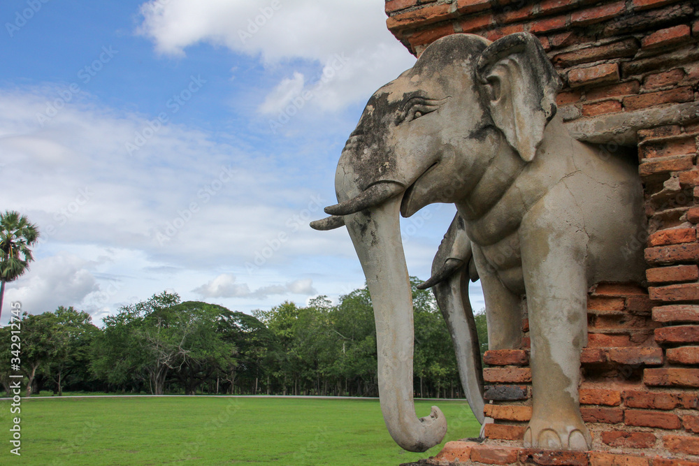 Naklejka premium Stone elephant in Sukhothai with vegetation in the background