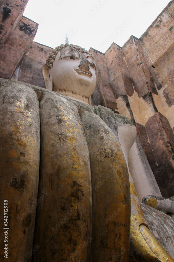 Buddha Wat Si Chum of Sukhothai stone with hand in foreground