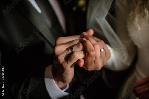 A young couple of Europeans in wedding rings holding hands at a wedding in the soft light of the setting sun