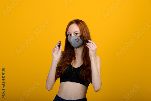 Portrait of a girl in a mask, which puts on a rubber glove. Yellow background. © Ivan Zelenin