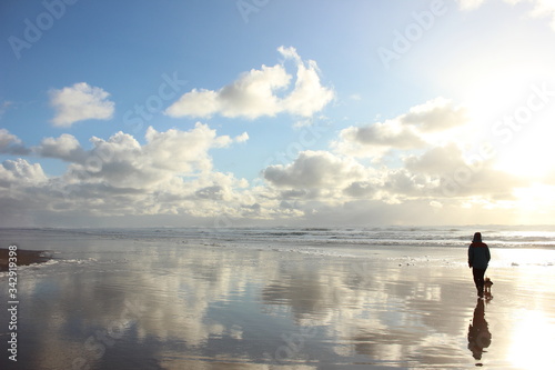 Man Walking With His Small Dog on Manzanita Beach on Pacific Coast in Oregon